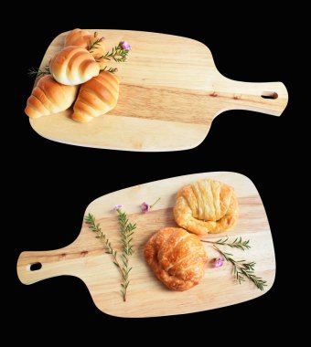 Tahta kesme tahtasına izole edilmiş peynirli kruvasan. Siyah arka planda gölge yok. Ev yapımı tatlı.