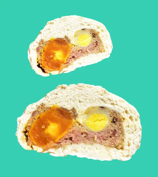 Baozi or Chinese steamed meat bun half isolated with pork meat and salted egg yolk and quail eggs in green background with clipping path and no shadow