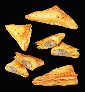 Puf böreği üçgeni izole edilmiş peynirli gevrek hamur işi kesme yolu olan domuz eti dolu, siyah arka planda gölge yok.