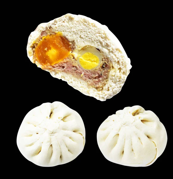 Baozi or Chinese steamed meat bun half isolated filled with pork meat and salted egg yolk and quail eggs in black background with clipping path and no shadow