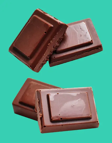 Milk chocolate pieces isolated with clipping path, no shadow in green background, cooking ingredient, homemade sweet dessert