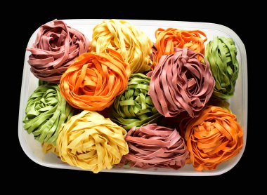 Renkli İtalyan tagliatelle veya Fettuccine makarnası klasik istif, yuva yumurtası İtalyan makarnası kırpma yolu izole, siyah arka planda gölge yok, yemek malzemesi yok