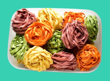 Renkli İtalyan tagliatelle ya da Fettuccine makarnası klasik istif. Yuva yumurtası, kırpma yolu ile izole edilmiş İtalyan makarnası. Yeşil arka planda gölge yok.