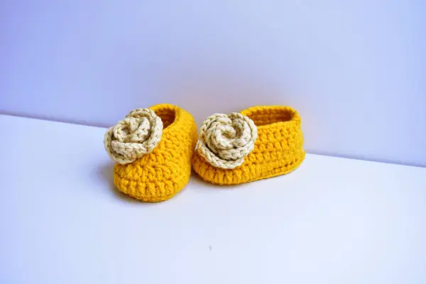 Crochet newborn baby girl shoes or pair of handmade booties for kids isolated in white background, pregnancy motherhood concept, first birthday party banner