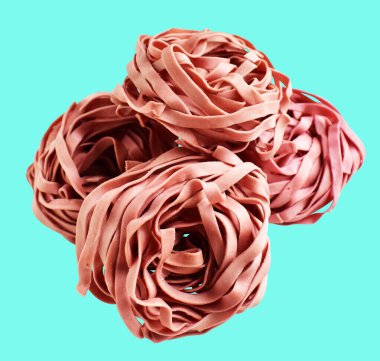 Pembe veya mor makarna yuvası veya İtalyan tagliatelle veya Fettuccine makarna klasik yığın, kırpma yolu ile izole edilmiş yuva yumurtası İtalyan makarnası, yeşil arka planda gölge yok, yemek malzemesi yok.
