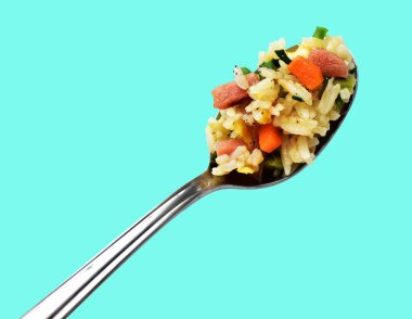 Kırpılmış bir kaşık kızarmış pirinç, yeşil arka planda gölge yok. Çin pilavı, karışık sebze, yumurta ve sosis (Yangzhou tarzı).)