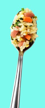 Kırpılmış bir kaşık kızarmış pirinç, yeşil arka planda gölge yok. Çin pilavı, karışık sebze, yumurta ve sosis (Yangzhou tarzı).)