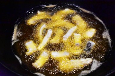 Kızarmış fileto balığı parçaları sıcak yağ tavasında, pişirme işlemi, yakın plan, siyah arkaplan