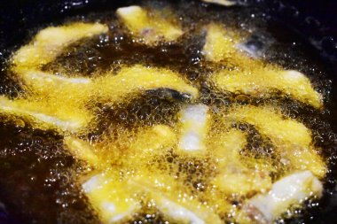 Kızarmış fileto balığı parçaları sıcak yağ tavasında, pişirme işlemi, yakın plan, siyah arkaplan