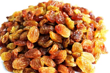 Beyaz arka planda izole edilmiş sarı ve kahverengi kuru üzüm yığınları. Güneşli ve parlak.