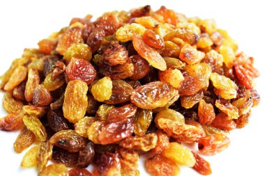 Beyaz arka planda izole edilmiş sarı ve kahverengi kuru üzüm yığınları. Güneşli ve parlak.