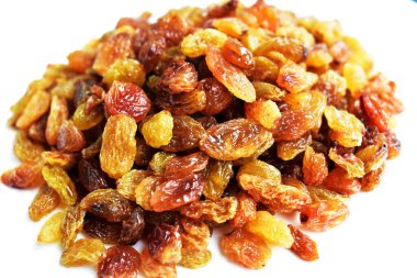 Beyaz arka planda izole edilmiş sarı ve kahverengi kuru üzüm yığınları. Güneşli ve parlak.