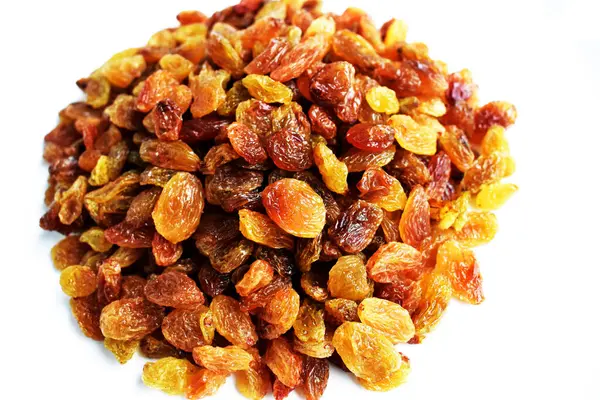 Beyaz arka planda izole edilmiş sarı ve kahverengi kuru üzüm yığınları. Güneşli ve parlak.