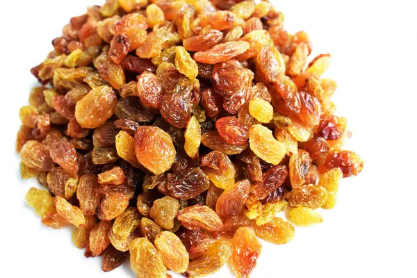 Beyaz arka planda izole edilmiş sarı ve kahverengi kuru üzüm yığınları. Güneşli ve parlak.