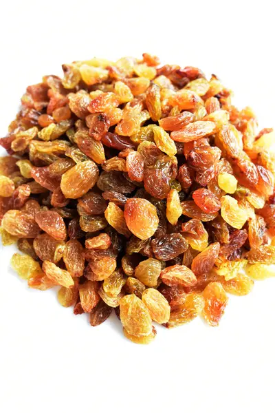 Beyaz arka planda izole edilmiş sarı ve kahverengi kuru üzüm yığınları. Güneşli ve parlak.