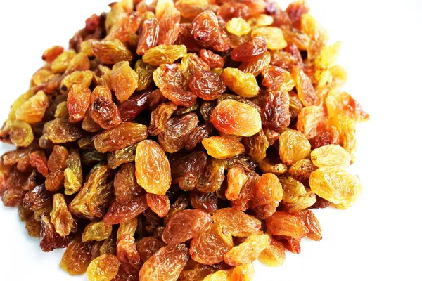 Beyaz arka planda izole edilmiş sarı ve kahverengi kuru üzüm yığınları. Güneşli ve parlak.