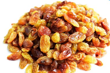 Beyaz arka planda izole edilmiş sarı ve kahverengi kuru üzüm yığınları. Güneşli ve parlak.