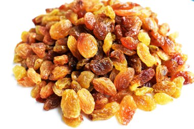 Beyaz arka planda izole edilmiş sarı ve kahverengi kuru üzüm yığınları. Güneşli ve parlak.