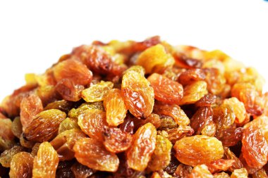 Beyaz arka planda izole edilmiş sarı ve kahverengi kuru üzüm yığınları. Güneşli ve parlak.