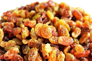 Beyaz arka planda izole edilmiş sarı ve kahverengi kuru üzüm yığınları. Güneşli ve parlak.