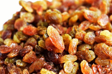 Beyaz arka planda izole edilmiş sarı ve kahverengi kuru üzüm yığınları. Güneşli ve parlak.