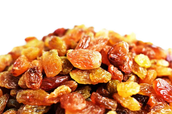 Beyaz arka planda izole edilmiş sarı ve kahverengi kuru üzüm yığınları. Güneşli ve parlak.