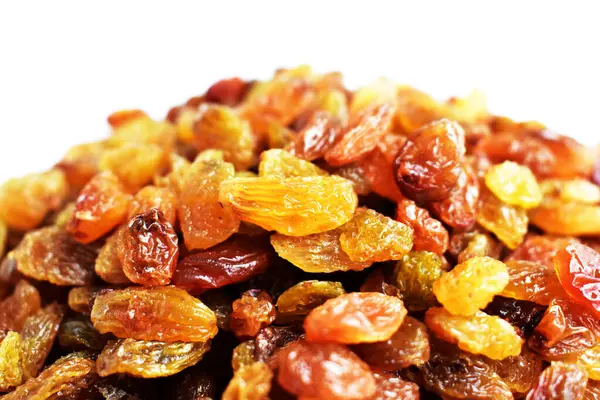 Beyaz arka planda izole edilmiş sarı ve kahverengi kuru üzüm yığınları. Güneşli ve parlak.