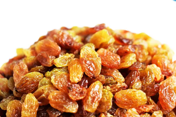 Beyaz arka planda izole edilmiş sarı ve kahverengi kuru üzüm yığınları. Güneşli ve parlak.