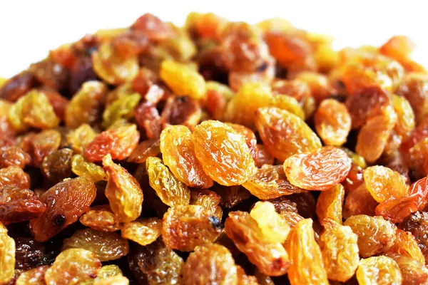 Beyaz arka planda izole edilmiş sarı ve kahverengi kuru üzüm yığınları. Güneşli ve parlak.