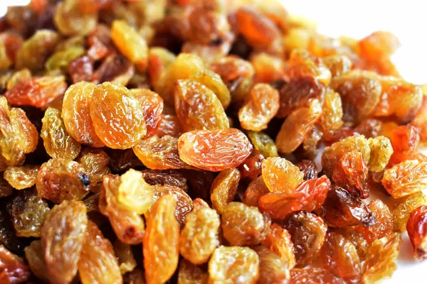 Beyaz arka planda izole edilmiş sarı ve kahverengi kuru üzüm yığınları. Güneşli ve parlak.