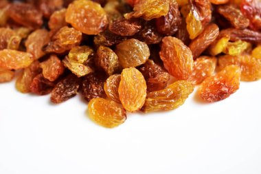 Beyaz arka planda izole edilmiş sarı ve kahverengi kuru üzüm yığınları. Güneşli ve parlak.
