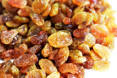 Beyaz arka planda izole edilmiş sarı ve kahverengi kuru üzüm yığınları. Güneşli ve parlak.