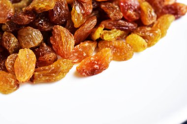 Beyaz arka planda izole edilmiş sarı ve kahverengi kuru üzüm yığınları. Güneşli ve parlak.