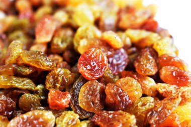 Beyaz arka planda izole edilmiş sarı ve kahverengi kuru üzüm yığınları. Güneşli ve parlak.