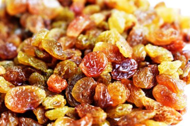 Beyaz arka planda izole edilmiş sarı ve kahverengi kuru üzüm yığınları. Güneşli ve parlak.