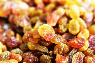 Beyaz arka planda izole edilmiş sarı ve kahverengi kuru üzüm yığınları. Güneşli ve parlak.