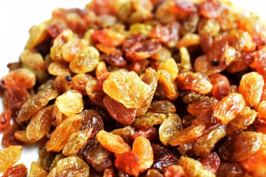 Beyaz arka planda izole edilmiş sarı ve kahverengi kuru üzüm yığınları. Güneşli ve parlak.