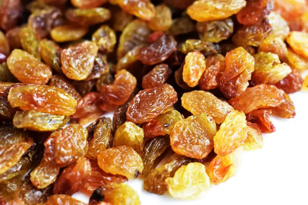 Beyaz arka planda izole edilmiş sarı ve kahverengi kuru üzüm yığınları. Güneşli ve parlak.