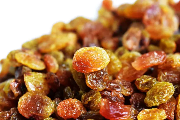 Beyaz arka planda izole edilmiş sarı ve kahverengi kuru üzüm yığınları. Güneşli ve parlak.