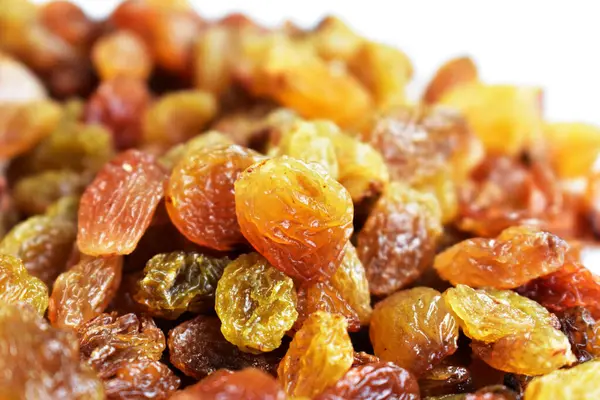 Beyaz arka planda izole edilmiş sarı ve kahverengi kuru üzüm yığınları. Güneşli ve parlak.