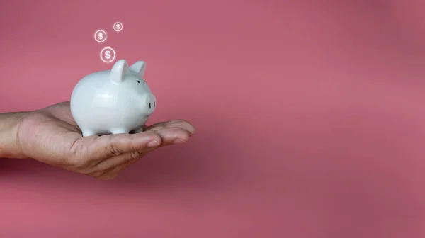 ピンクの背景に白い貯金箱を持って手 貯蓄と投資の概念 — ストック写真