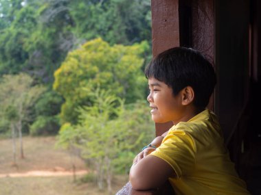 boy looking out window looking at the green forest