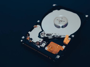 Bilgisayarın ya da dizüstü bilgisayarın parçalanmış sabit disk sürücüsü koyu mat yüzeyde yatıyor. Bilgisayar donanımı ve ekipmanı. Harddisk veri depolama.