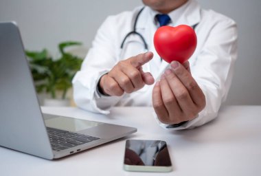 Hastane ofisinde kırmızı kalp gösteren bir doktor. Sağlık ve doktor hizmetleri konsepti.