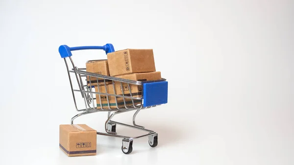 Alışveriş konsepti. Beyaz arka planda mavi alışveriş arabasında karton kutular. Çevrimiçi alışveriş tüketicileri evden ve teslimat servisinden alışveriş yapabilirler. kopyalama alanı ile