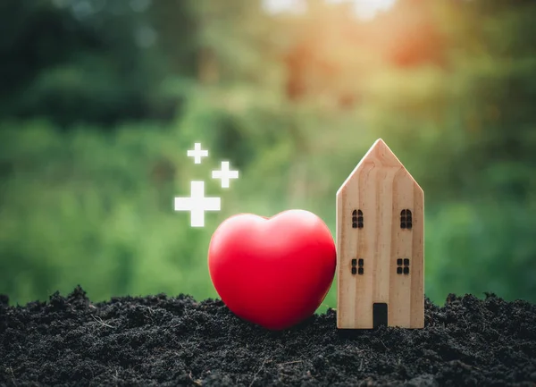 The concept of health insurance and medical welfare. Model wooden house and red heart with plus icon. Health insurance and access to health care. health care planning
