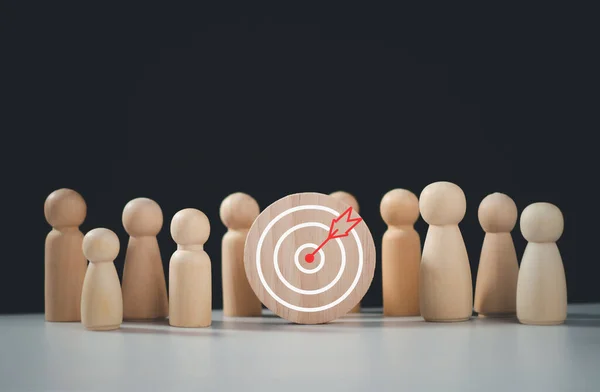 Target concept of business and personnel in a company. wooden dolls standing around Dart board and arrows for creating and targeting business objectives. Marketing solutions, targets for business investment.