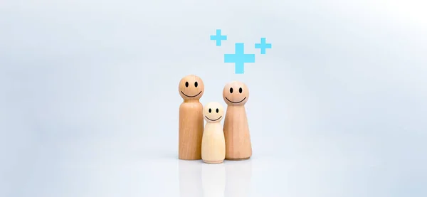 The concept of health insurance and Medical welfare. A family of wooden dolls with a plus sign on a white background represents protection, receiving benefits. health care planning