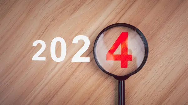2024 trend. Bir büyüteçin en üst görüntüsü içinde 2024 rakamları olan ahşap bir masaya yerleştiriliyor. Yeni yıl konsepti. 2024 gol konsepti. 2024 gol aranıyor.