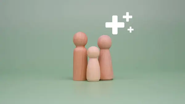 The concept of health insurance and medical welfare. Family of model wooden doll and plus sign on a green background. Health insurance and access to health care. health care planning
